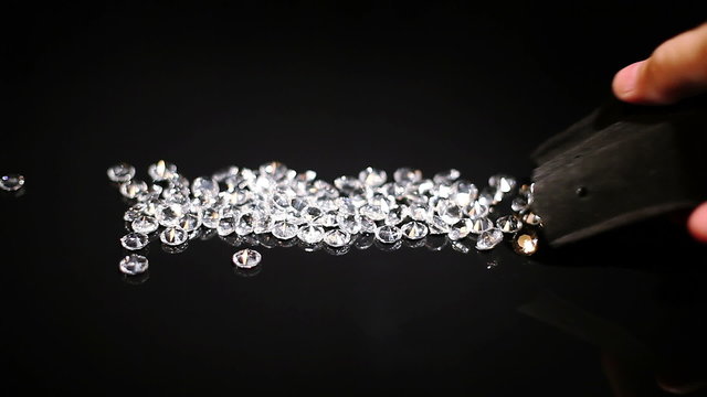 Diamonds spilling out of the bag on a black table