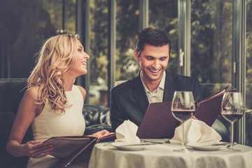 Fröhliches Paar mit Menü in einem Restaurant