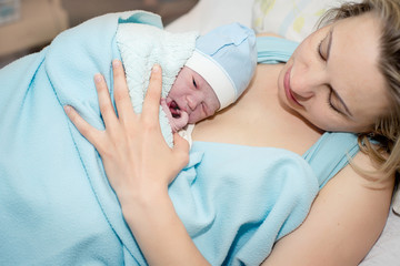 Young beautiful woman with a newborn baby after birth