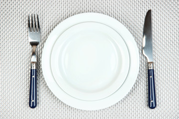 Knife, color plate and fork, on color background
