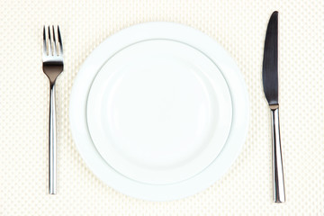 Knife, color plate and fork, on color background