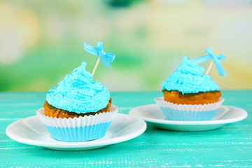 Tasty cup cakes with cream on blue wooden table