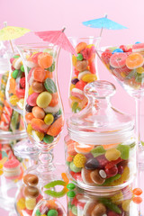 Different colorful fruit candy in glasses on pink background