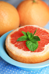 Ripe grapefruits in bowl on color wooden background
