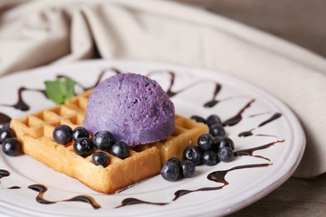 Tasty belgian waffles with ice cream on wooden table