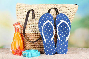 Summer wicker bag with accessories on sand, on nature
