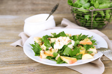 Green salad with apples, walnuts and cheese on wooden