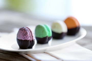 Colorful macaroons in plate on wooden table, close-up