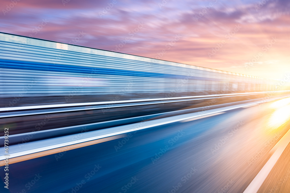 Wall mural Car driving on freeway at sunset, motion blur