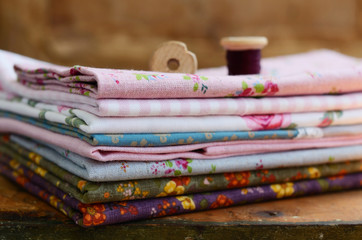 Stack of floral pattern textile and wooden spools - 67739441