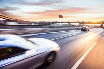 Photo sur Aluminium Voitures rapides Voiture roulant sur autoroute au coucher du soleil, flou de mouvement
