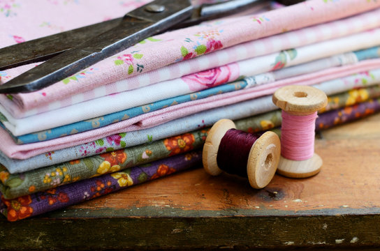 Set of fabrics, wooden thread spools and tailor scissors