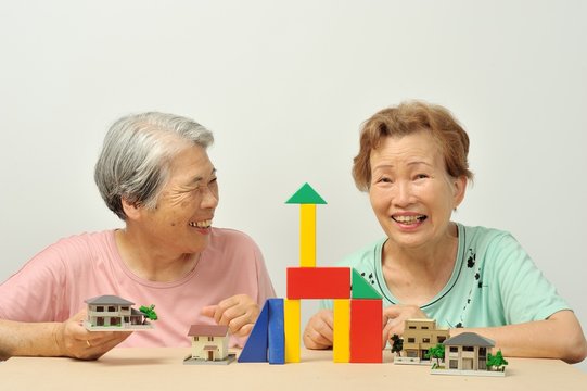 積み木と家の模型で遊んでいる二人のアジア人高齢者