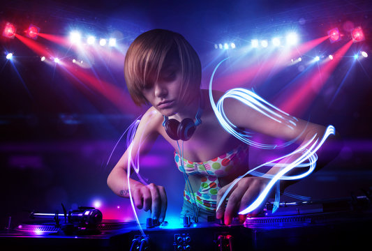 Disc jockey girl playing music with light beam effects on stage