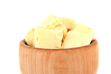 Butter pieces in wooden bowl, isolated on white