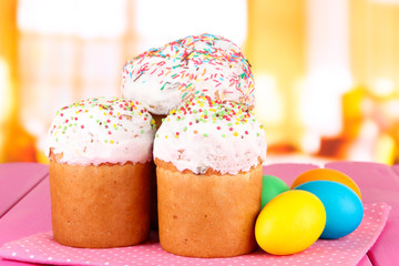Sweet Easter cakes with colorful eggs on table in room