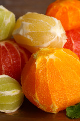 Citrus fruits without skin on tray, on wooden background