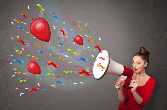 Young girl having fun, shouting into megaphone with balloons
