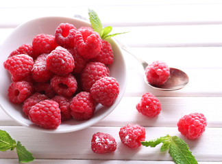 Ripe sweet raspberries in bowl on table close-up