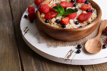 Tasty oatmeal with berries on table close-up