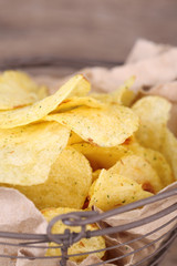 Tasty potato chips in metal basket  on wooden table