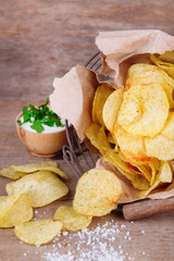 Tasty potato chips in metal basket  on wooden table