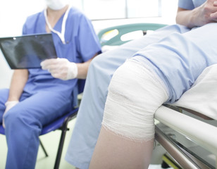 Obraz premium Patient with a knee injury and the doctor with x-ray in hands