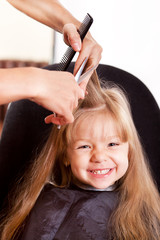 Naklejka premium Happy little girl at the hairdresser