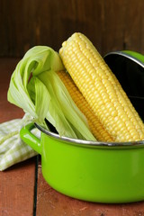 ripe yellow corn and green pan on a wooden background © Olga Kriger