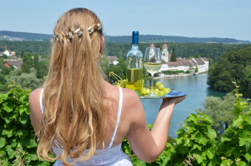 Girl holding wine and grapes against Rhine rive in Rheinau, Swit