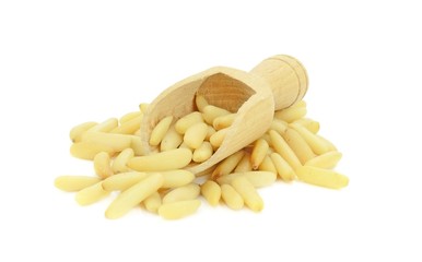 A pile of pine nuts and wooden scoop on white background