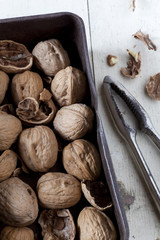 whole and cracked walnuts with nutcracker on vintage box
