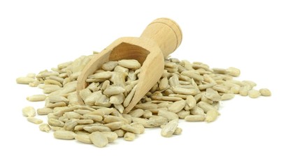 A pile of sunflower seeds and wooden scoop on a white background