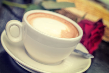 Blurred white cup of coffee with rose