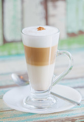 Frothy, layered cappuccino in a clear glass mug