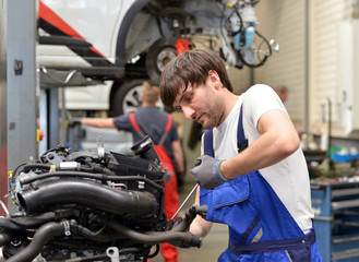 Fototapeta na wymiar Mechaniker repariert Motor in Werkstatt // succesfull workman