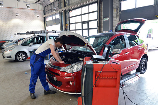 KFZ Mechaniker prüft Motor // mechanic in car workshop