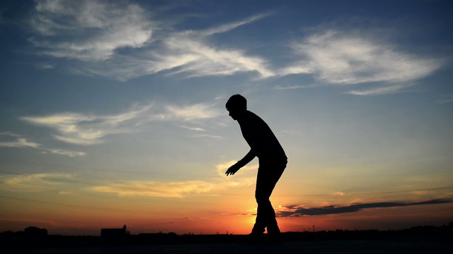 Silhouette of young adult woman smoking a cigarette in sunset