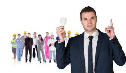 Composite image of businessman holding light bulb and pointing