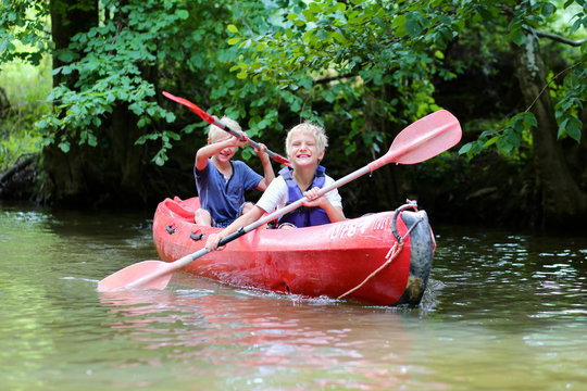Two happy school boys kayaking on the river