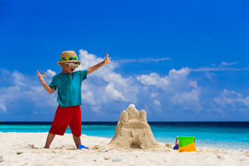 happy child with built sand castle on the beach