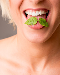 Closeup of lips with red lipstick holding peppermin