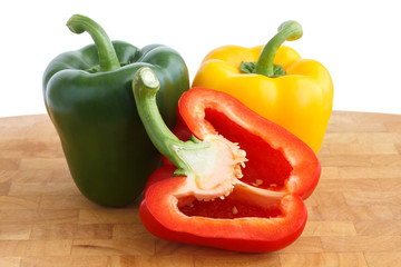 Red, yellow, green peppers on chopping board. Cut in half.
