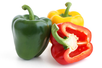 Red, yellow, green peppers on white. Red pepper cut in half.