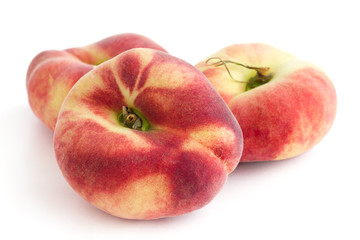 Group of ripe flat peaches on white