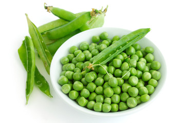 Fresh garden peas in a ceramic dish shot from above.With pods.