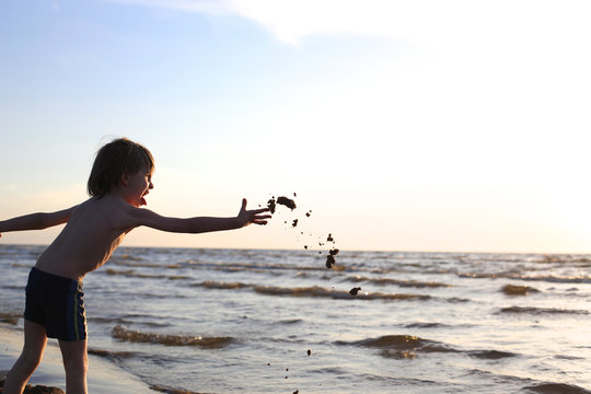 Boy Throwing Sand To The Sea With Disgust