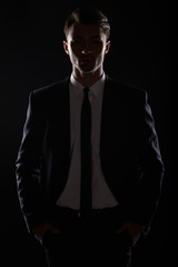 Handsome business man in black suite, backlight