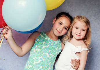 cute sisters with colorful balloons