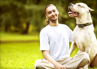 Man and Dogo Argentino walk in the park.